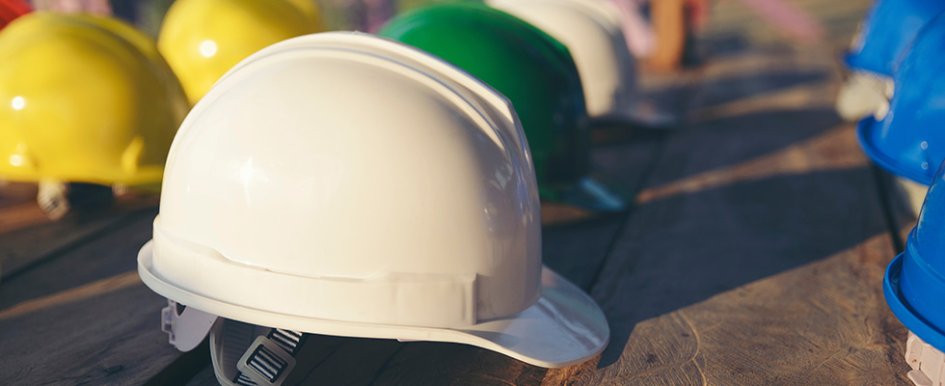 White hard hat in foreground surrounded by colorful hard hats