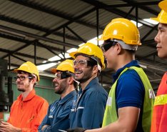 Construction workers in hard hats and goggles smiling / Adobe Stock