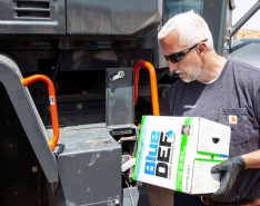 Man pours diesel exhaust fluid into a large piece of equipment
