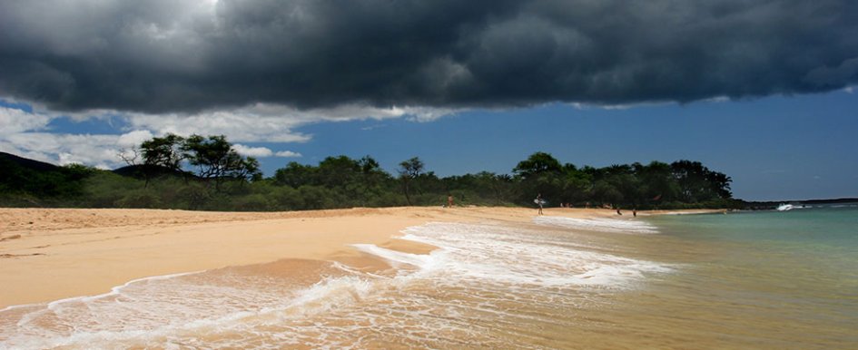 Waves rolling onto beach with storm clouds overhead