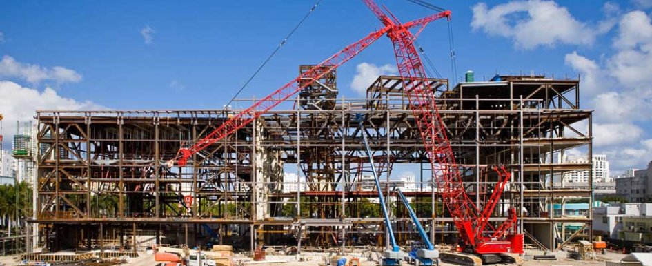 A large red crane sits in front of a building under consruction