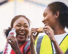Two women in vests laughing/Adobe Stock 