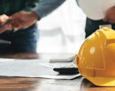 hard hat and papers on a desk to represent job costing/Adobe Stock