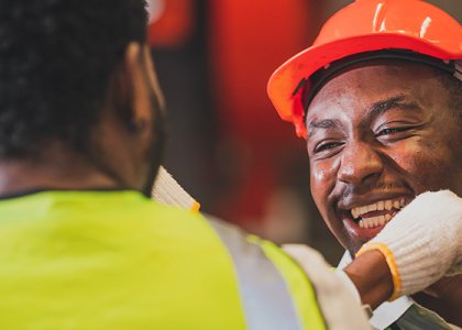 People in vests and hard hats smiling/Adobe Stock